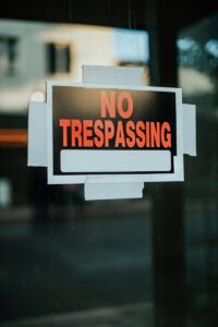 A prominently displayed no trespassing sign taped to a glass door emphasizes property boundaries.